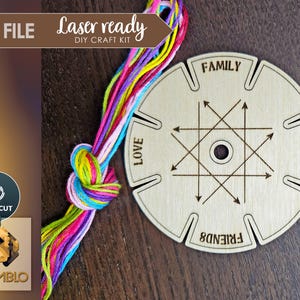 Puede incluir: Un aro de bordado de madera con ocho ranuras para hilo. Las ranuras est&aacute;n etiquetadas como "Familia", "Amor", "Hogar" y "Amigos". El aro est&aacute; rodeado de hilo de bordar de colores.