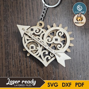 May include: A wooden heart-shaped keychain with an arrow through it, engraved with the text "YOU ARE THE REASON MY HEART KEEPS TURNING". The keychain also has the text "I LOVE YOU". The keychain is attached to a silver keyring.