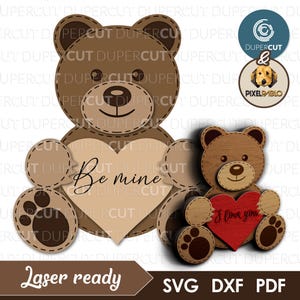 Könnte beinhalten: Ein lasergeschnittenes Holzhandwerksprojekt mit zwei Teddybären. Der größere Bär hält ein herzförmiges Schild mit der Aufschrift "Be mine". Der kleinere Bär hält ein herzförmiges Schild mit der Aufschrift "I love you".