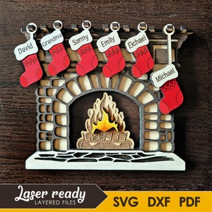Puede incluir: Decoración navideña de chimenea de madera con seis calcetines rojos etiquetados "David", "Grandma", "Sarmy", "Emily", "Eichael" y "Michael". La chimenea tiene una fachada de piedra y un fuego recortado. También se ve el texto "Laser ready" y "SVG DXF PDF".