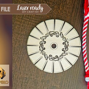 May include: A wooden circle with a decorative floral design and slots around the edge. The circle is on a brown wooden surface. The text "Laser ready DIY Craft Kit" is on a white banner above the circle.