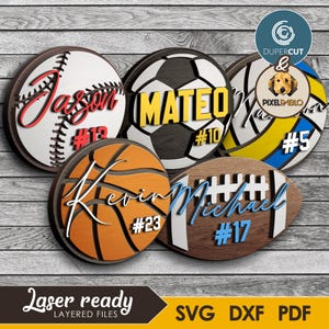 May include: A collection of layered wooden sports-themed signs. Each sign features a different sport: baseball, soccer, basketball, volleyball, and football. Names and numbers are displayed on each sign. The text "Laser ready" and file type options are also visible.