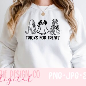 K&ouml;nnte beinhalten: Ein wei&szlig;er Pullover mit einer schwarzen Grafik von drei Hunden, die als Geister f&uuml;r Halloween verkleidet sind. Der Text "TRICKS FOR TREATS" befindet sich unter den Hunden.