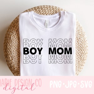 May include: White t-shirt with the words "BOY MOM" in a stacked design. The word "BOY" is on the left, and "MOM" is on the right. The shirt is on a woven, circular surface. The text "MARIE DESIGN CO digital" is at the bottom.