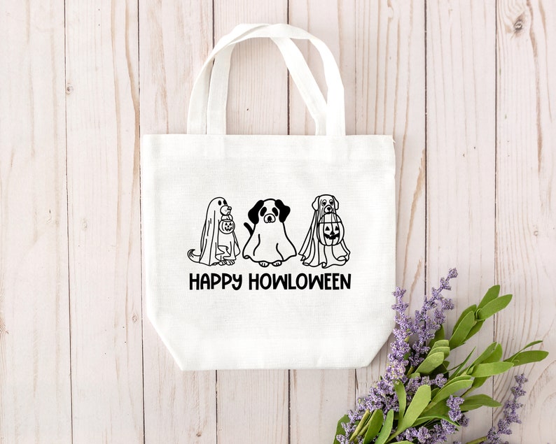 K&ouml;nnte beinhalten: Wei&szlig;e Einkaufstasche mit schwarzen Strichzeichnungen von drei Hunden, die als Geister f&uuml;r Halloween verkleidet sind. Der Text "Happy Howloween" ist unter den Hunden gedruckt.