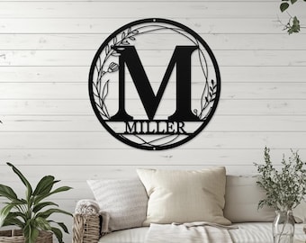 May include: Black metal monogram with floral accents and the name "MILLER" below the letter "M".