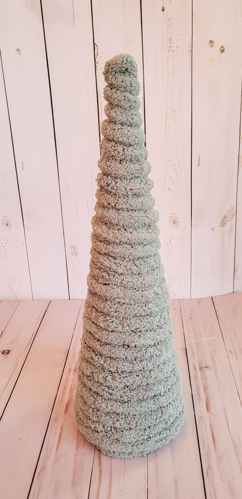 K&ouml;nnte beinhalten: Ein hellblauer, kegelf&ouml;rmiger Dekobaum aus weichem, strukturiertem Material. Der Baum ist etwa 30 cm hoch und hat ein spiralf&ouml;rmiges Design. Er steht vor einem hellen Holzhintergrund.