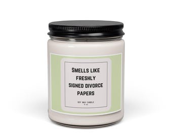 Puede incluir: Una vela de cera de soja de 9 oz en un frasco de vidrio transparente con tapa de metal negro. La etiqueta tiene un fondo verde claro con un borde rectangular blanco y texto negro: SMELLS LIKE FRESHLY SIGNED DIVORCE PAPERS SOY WAX CANDLE 9 oz.