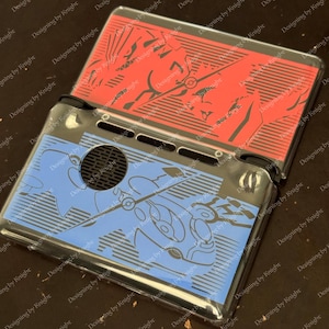 Könnte beinhalten: Eine transparente Nintendo DS-Schutzhülle mit roter Oberseite und blauem Boden. Die rote Oberseite hat ein schwarzes Grafikdesign, während die blaue Unterseite ein anderes schwarzes Grafikdesign aufweist. Die Hülle dient zum Schutz des Nintendo DS.