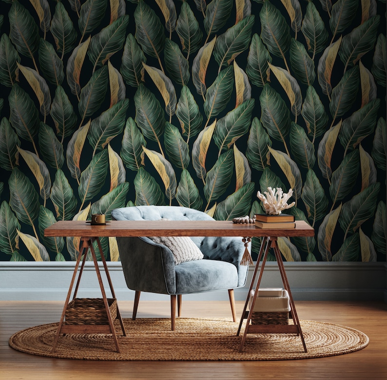 Peut inclure: Un fauteuil en velours bleu avec une structure en bois se trouve devant un papier peint vert fonc&eacute; avec des accents de feuilles d'or. Un bureau en bois avec une finition en bois clair est plac&eacute; devant la chaise. Le bureau est soutenu par deux chevalets en bois. Un petit panier tiss&eacute; se trouve sur l'&eacute;tag&egrave;re inf&eacute;rieure des chevalets. Le bureau est d&eacute;cor&eacute; d'une petite tasse en c&eacute;ramique blanche, de deux livres et d'un petit morceau de corail.