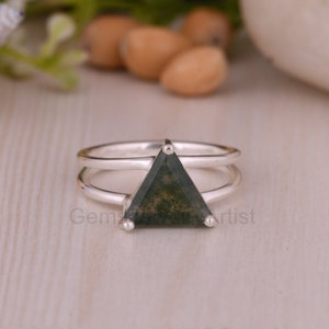 Op de afbeelding: Een zilveren ring met een donkergroene driehoekige edelsteen. De ring heeft een dubbele band.