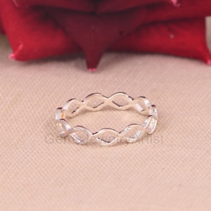 May include: A silver ring with a delicate, openwork design. The ring is made of a series of interconnected ovals.