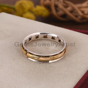 Könnte beinhalten: Ein silberner Ring mit einem goldenen Band und einer Reihe von Sternen um die Mitte.