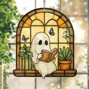 May include: A stained glass window hanging ornament featuring a ghost reading a book in a window with plants and butterflies.