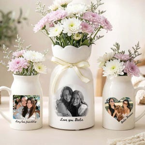 May include: Three white ceramic vessels filled with white and pink chrysanthemums. Two mugs feature heart-shaped photo prints with text reading Long live friendship and Bestie Forever. A central vase has a ribbon and photo print with text Love you Bestie.