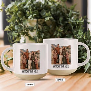 May include: Two white ceramic mugs with a family photo printed on them. The mugs have a beige base and a white handle. The front of the mug says "CUSTOM TEXT HERE". The back of the mug also has a family photo.