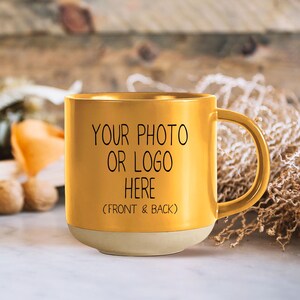 Op de afbeelding: Een gouden keramische mok met een handvat. Op de mok staat de tekst "YOUR PHOTO OR LOGO HERE (FRONT & BACK)".