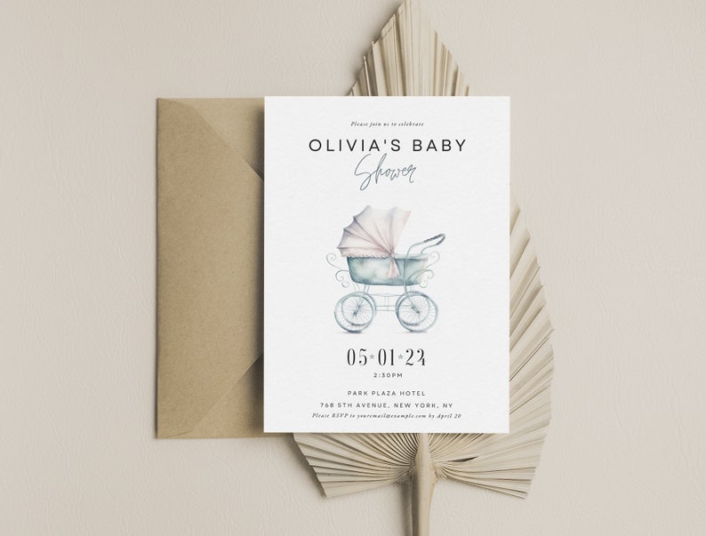 Op de afbeelding: Babyborrel uitnodiging met een aquarel illustratie van een vintage kinderwagen in zachte blauwe en roze tinten. De uitnodiging bevat de tekst "OLIVIA'S BABY Shower" en evenement details. Een kraft papieren envelop en gedroogd palmblad maken het ontwerp compleet.