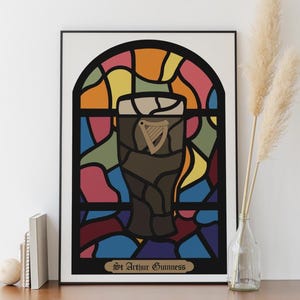 May include: A framed print of a stained glass window design featuring a glass of Guinness beer with the text "St. Arthur Guinness" at the bottom.