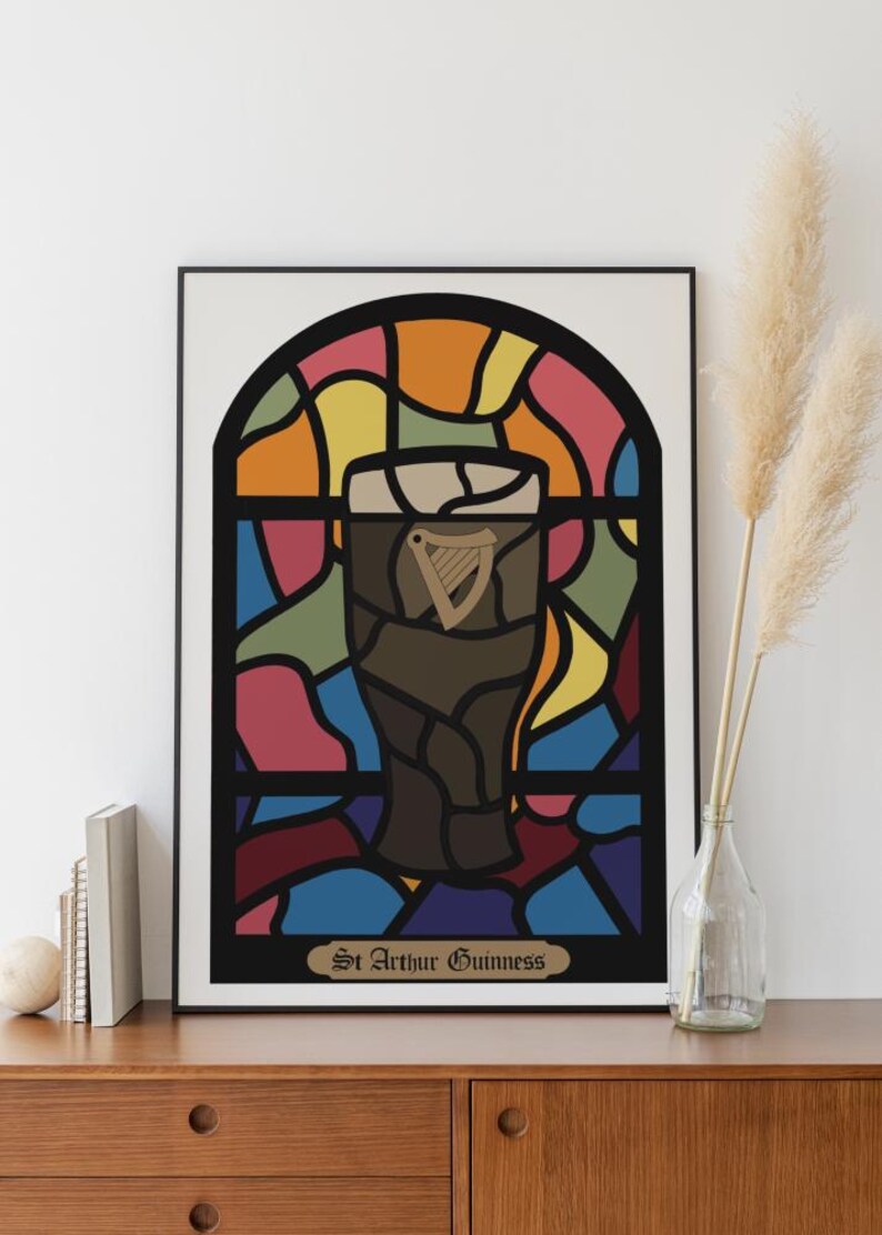 May include: A framed print of a stained glass window design featuring a glass of Guinness beer with the text "St. Arthur Guinness" at the bottom.