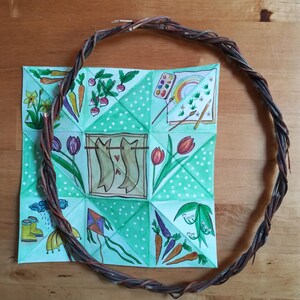 Può includere: Un gioco di indovinelli di carta verde con pois bianchi e illustrazioni di immagini a tema primaverile, tra cui fiori, pioggia, carote, un aquilone, un arcobaleno e un paio di pesci. Il gioco di indovinelli è circondato da una ghirlanda di ramoscelli marroni.