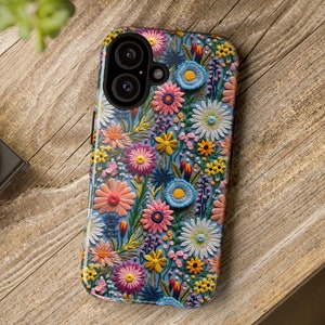 May include: A phone case with a floral pattern. The case is black and has a blue background with colorful flowers. The case has a camera cutout.
