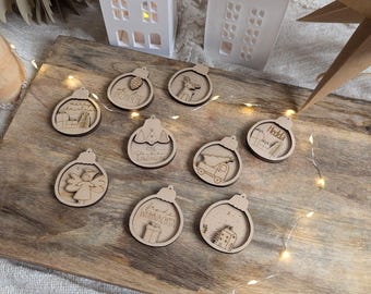 May include: Ten wooden Christmas ornaments with various designs, including a Christmas tree, a house, a reindeer, a truck, an angel, and a gift box. The ornaments are all in a natural wood color and have white lettering.