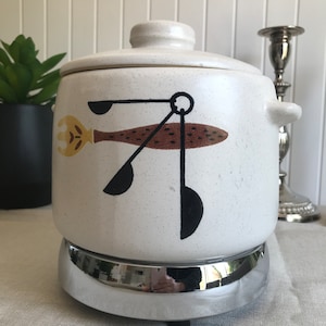 May include: White ceramic slow cooker with a brown and black abstract design. The cooker has a chrome base and a lid.