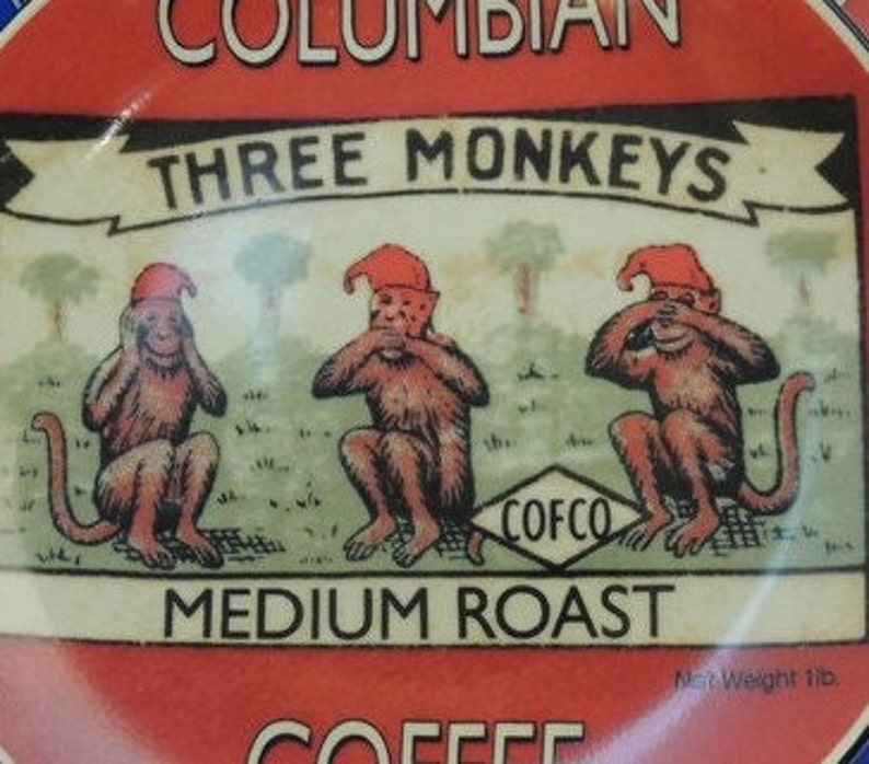 May include: A red and white coffee can with a picture of three monkeys wearing red hats. The monkeys are covering their eyes, ears, and mouth. The can says "Columbian Three Monkeys Medium Roast Coffee" and "COFCO".