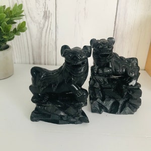 以下が含まれることがあります： 黒く彫刻された石のフー・ドッグの置物2体。フー・ドッグは台座の上に座っており、獰猛な表情をしています。