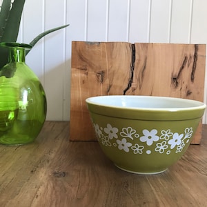 Peut inclure: Un bol mélangeur vert avec un motif floral blanc. Le bol est en céramique et a une finition lisse et brillante.