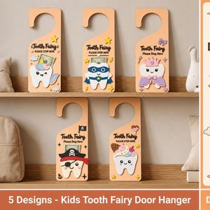 May include: Five wooden door hangers featuring Tooth Fairy designs with pockets for money. Each hanger displays a unique tooth character: a unicorn, a superhero, a princess, a pirate, and an ice cream cone, with text reading Tooth Fairy Please Stop Here.