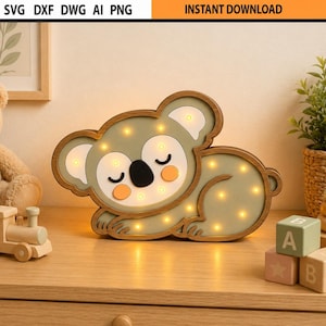 May include: A wooden koala night light with a soft glow. The koala has a light green body, a black nose, and orange cheeks. The text "INSTANT DOWNLOAD" is at the top. Other toys are in the background.