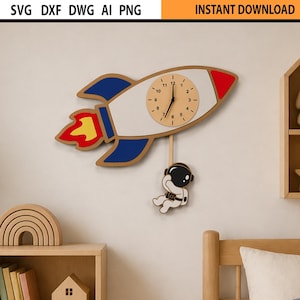 May include: A wooden rocket-shaped wall clock with a beige clock face, red and blue accents, and a dangling astronaut figure. The clock is mounted on a light-colored wall, with a wooden shelf and other decorative items in the background. The text "INSTANT DOWNLOAD" is at the top.
