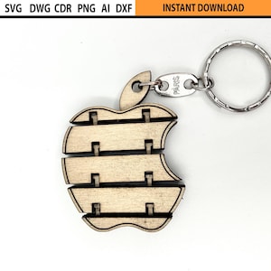 May include: Wooden apple-shaped keyring with a bite taken out, attached to a silver ring. The apple design is made of layered wooden pieces. Text at the top reads "SVG DWG CDR PNG AI DXF" and "INSTANT DOWNLOAD".