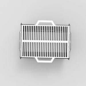 Puede incluir: Vista superior de una parrilla rectangular de metal blanco con ranuras verticales. Tiene dos asas en los laterales y una en cada extremo. La parrilla est&aacute; sobre un fondo liso de color gris claro.