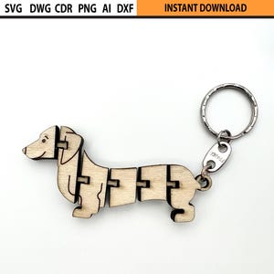 May include: A wooden dachshund keychain with a silver keyring. The dachshund is made of interlocking pieces of light-colored wood. The top of the image has the text "SVG DWG CDR PNG AI DXF" and "INSTANT DOWNLOAD".