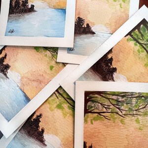May include: A collection of watercolor landscape paintings. Each painting features a serene scene with a body of water, trees, and a colorful sky. The paintings are on white paper and signed with the initials "djb".