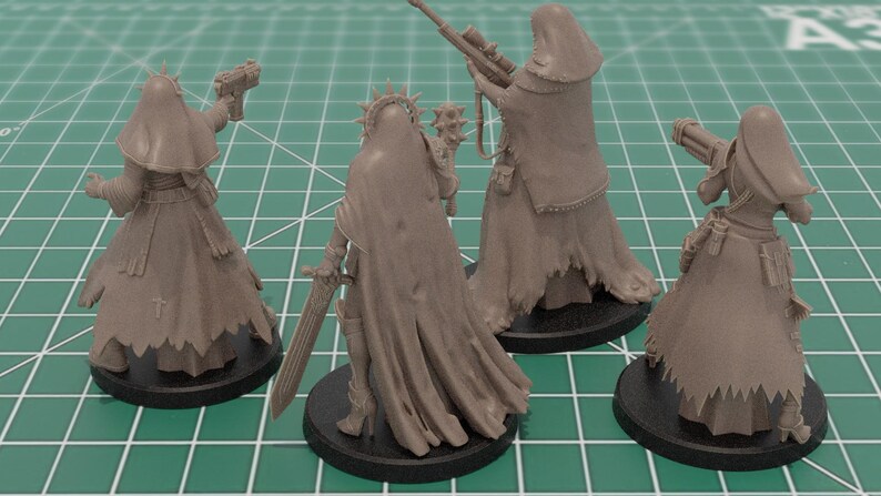 Op de afbeelding: Vier ongeverfde grijze miniatuurfiguren van hars op ronde zwarte voetstukken. Elke figuur draagt een kapmantel en draagt een wapen, waaronder een pistool, een strijdhamer, een sluipschuttersgeweer en een kanon, met gedetailleerde stoftexturen.