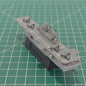 May include: A detailed model of a grey aircraft carrier with a black base. The model features miniature helicopters and other aircraft on the flight deck. The carrier is set against a green grid background.