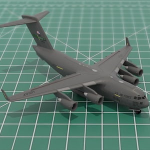 May include: A gray model airplane with the text "USAF" on the wing and "U.S. AIR FORCE" on the fuselage. The model has four engines on each wing and is set against a green grid background.