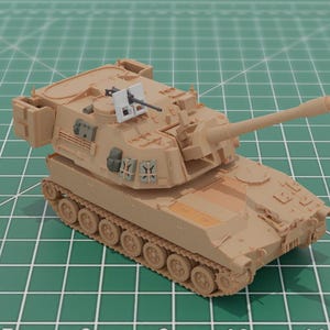Puede incluir: Maqueta beige de un tanque obús autopropulsado con un cañón largo y orugas detalladas. El modelo incluye una pequeña ametralladora y varios compartimentos. Se encuentra sobre una esterilla de corte verde con líneas de cuadrícula.