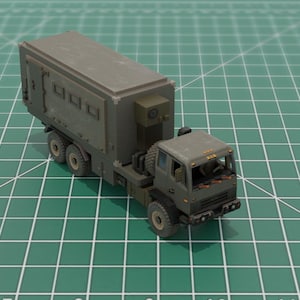 May include: A detailed model of a military truck, featuring a gray cab and a matching cargo container. The truck has multiple wheels and is set against a green grid background, suggesting a scale model or hobby item.