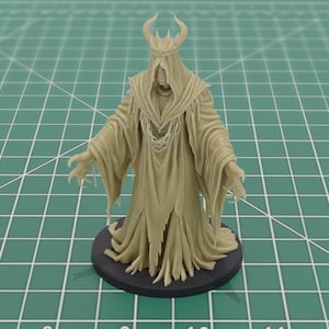 Puede incluir: Figura beige de una figura con túnica, corona y brazos extendidos. La figura tiene un diseño detallado, con una túnica fluida y una base circular oscura. Sobre un fondo de cuadrícula verde.