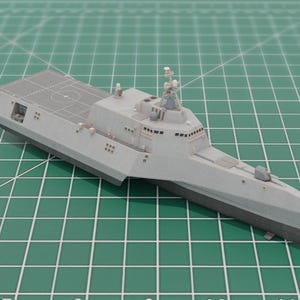 Puede incluir: Una taza de cerámica blanca con un asa negra y el texto "But First, Coffee" en negrita negra. La taza se encuentra sobre un fondo borroso, resaltando su diseño limpio.