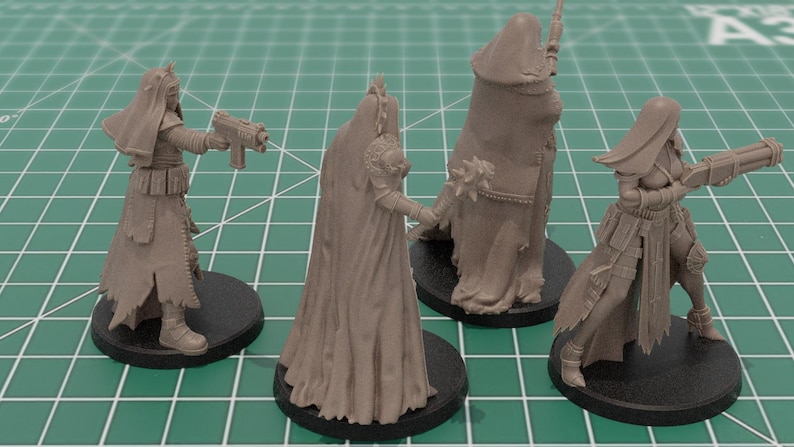 Op de afbeelding: Vier onbeschilderde grijze hars miniatuurfiguren op ronde zwarte voetstukken. De figuren dragen lange gewaden, sluiers en tactische uitrusting, waarbij er drie futuristische vuurwapens vasthouden en &eacute;&eacute;n een strijdknots met stekels in de hand houdt.