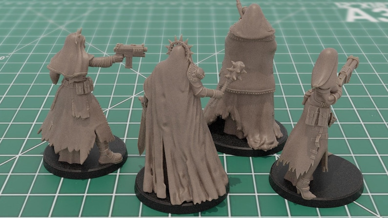 Op de afbeelding: Vier ongeverfde lichtbruine hars miniatuurfiguurtjes op ronde zwarte voetjes. De figuren dragen mantels met capuchon en gewaden, waarbij er &eacute;&eacute;n een pistool vasthoudt, &eacute;&eacute;n een knots met stekels en een andere een lang geweer. Gedetailleerde stoftexturen.