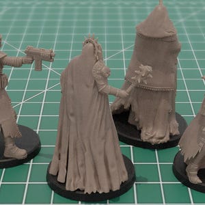 Op de afbeelding: Vier onbeschilderde miniatuurfiguren van grijze hars op zwarte ronde voetstukken. Twee figuren houden futuristische vuurwapens vast, &eacute;&eacute;n houdt een knots met stekels vast en &eacute;&eacute;n is gehuld in een mantel met capuchon. Gedetailleerde kleding en harnas.