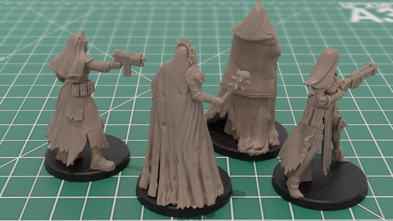 Op de afbeelding: Vier onbeschilderde miniatuurfiguren van grijze hars op zwarte ronde voetstukken. Twee figuren houden futuristische vuurwapens vast, &eacute;&eacute;n houdt een knots met stekels vast en &eacute;&eacute;n is gehuld in een mantel met capuchon. Gedetailleerde kleding en harnas.