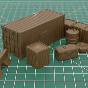 May include: A selection of miniature brown military models, including a shipping container, sandbag barriers, a barrel, a crate, a tyre, and other structures. The objects are arranged on a green grid surface.